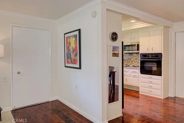 a view of kitchen with stainless steel appliances wooden floor and living room view