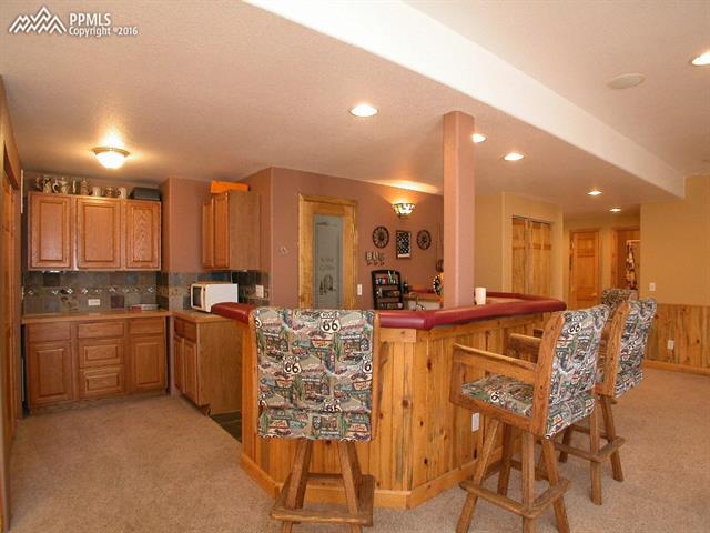 12153 Rio Secco Road Peyton, CO 80831 - Photo 20 of 26 Custom built wet bar with beetle kill pine wainscoting, custom tile, wine cellar & tons of storage. Bar stools are included.