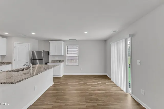 a large kitchen with a center island wooden floor and stainless steel appliances