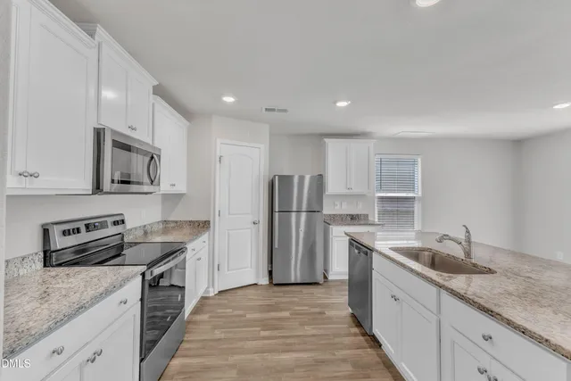 a kitchen with stainless steel appliances granite countertop a sink stove and refrigerator