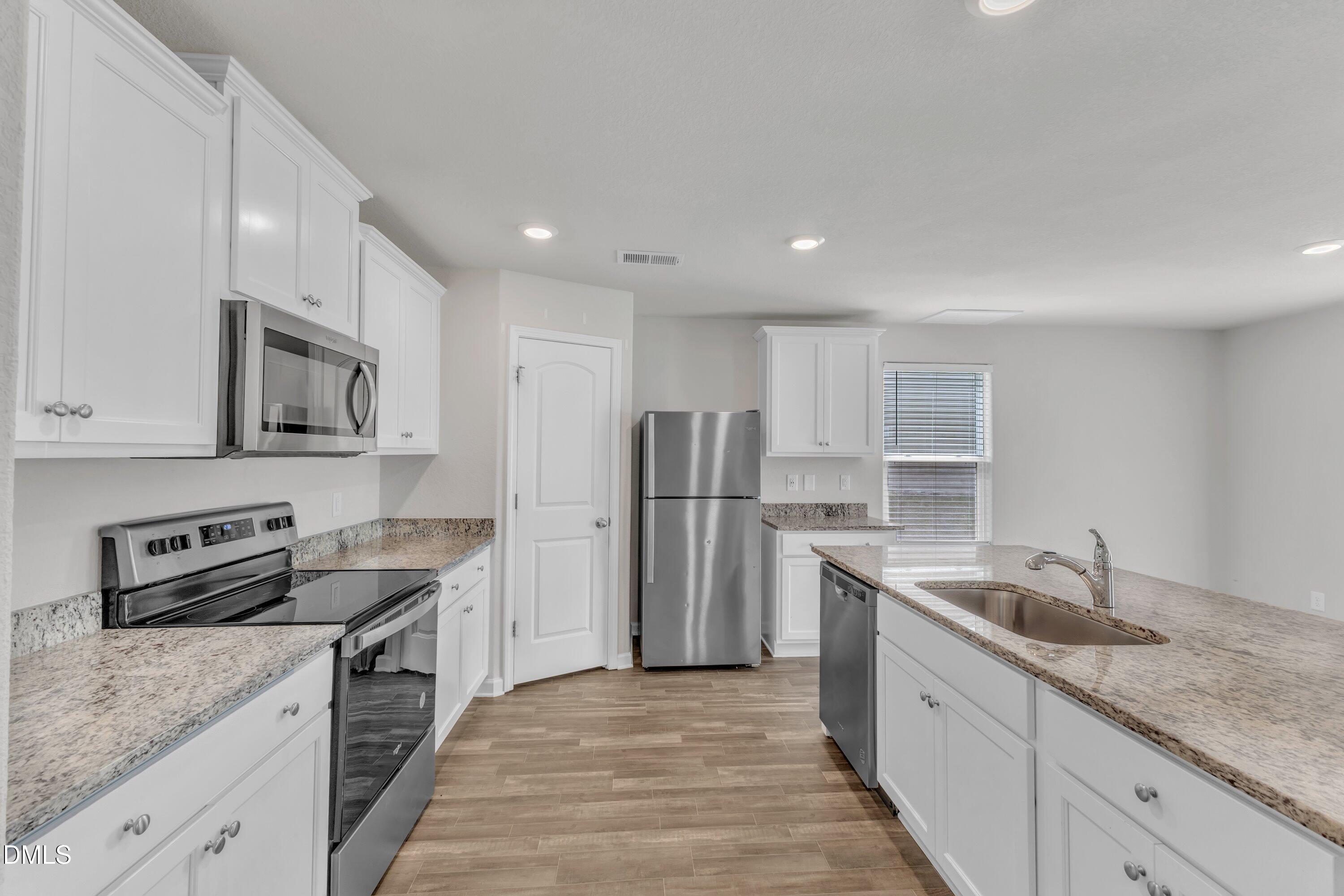 717 Little Patch Street Zebulon, NC 27597 - Photo 15 of 36 a kitchen with stainless steel appliances granite countertop a sink stove and refrigerator