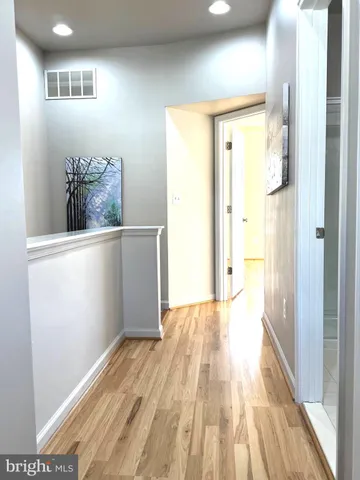 a view of a hallway with wooden floor and a cabinet