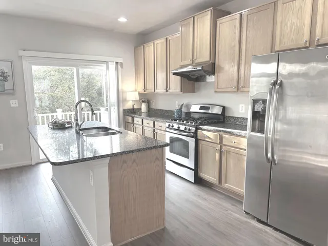 a kitchen with kitchen island granite countertop a sink a counter space appliances and cabinets