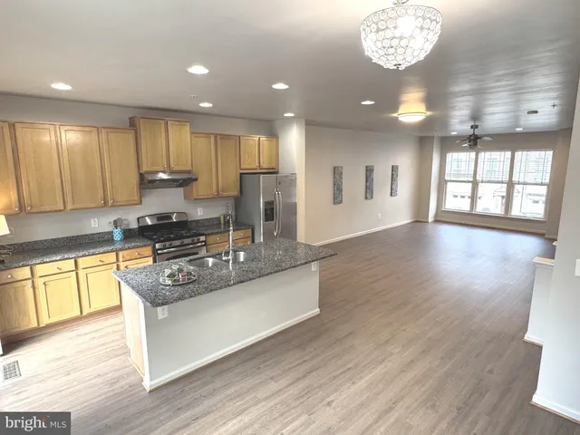 a large kitchen with stainless steel appliances granite countertop a stove and a wooden floors