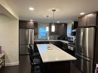 a kitchen with stainless steel appliances a refrigerator a sink a stove a dining table and chairs