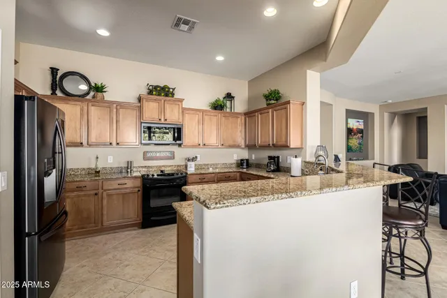 a kitchen with stainless steel appliances granite countertop a refrigerator a stove a sink and a microwave