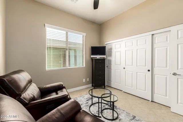 a bedroom with a bed table chair and a flat screen tv