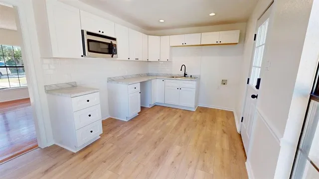 a kitchen with white cabinets and black appliances