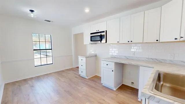 a kitchen with granite countertop white cabinets and sink
