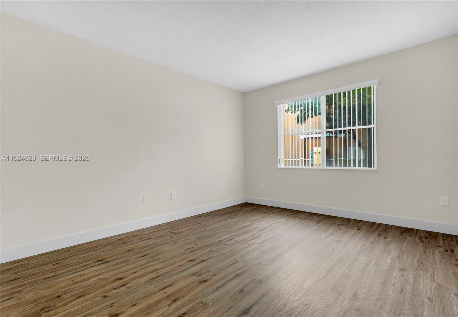 7250 Northwest 177th Street, Unit 10216 Hialeah, FL 33015 - Photo 14 of 23 a view of an empty room with wooden floor and a window
