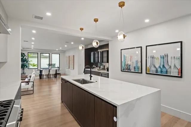 a large white kitchen with stainless steel appliances kitchen island granite countertop a large counter top and wooden floors