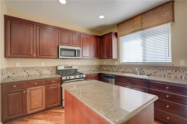 a kitchen with granite countertop cabinets stainless steel appliances a sink and a window