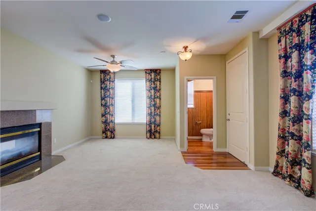 a view of an empty room with a fireplace and a fan