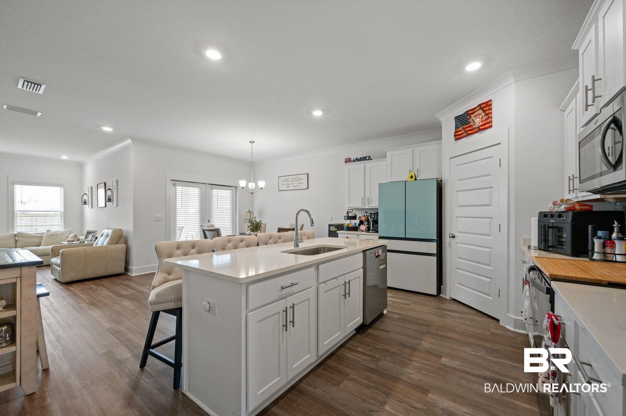 8508 Rosedown Lane Daphne, AL 36526 - Photo 28 of 29 Kitchen featuring white cabinetry, suspended lighting, open floor plan, a kitchen bar, and dark wood finished floors