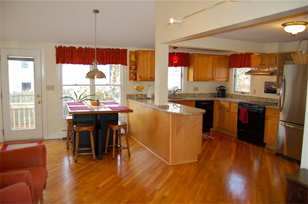 39 Shetland Road Marblehead, MA 01945 - Photo 2 of 12 a kitchen with stainless steel appliances granite countertop a stove top oven a sink dishwasher a dining table and chairs with wooden floor