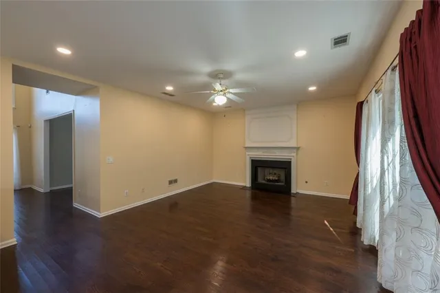 an empty room with wooden floor fireplace and windows