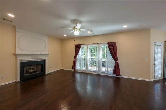 a view of an empty room with wooden floor fireplace and a window