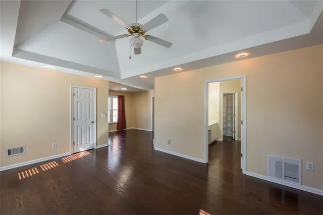 an empty room with wooden floor and ceiling fan