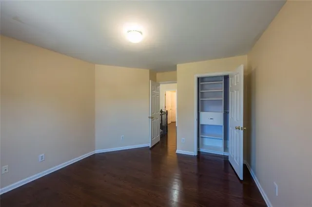 a view of an empty room with wooden floor and closet