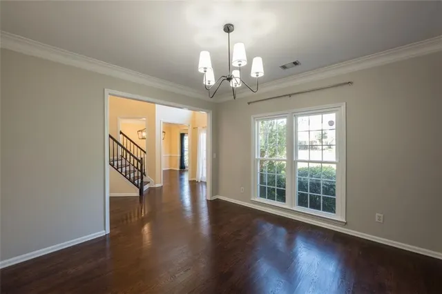 a view of a room with wooden floor chandelier and windows