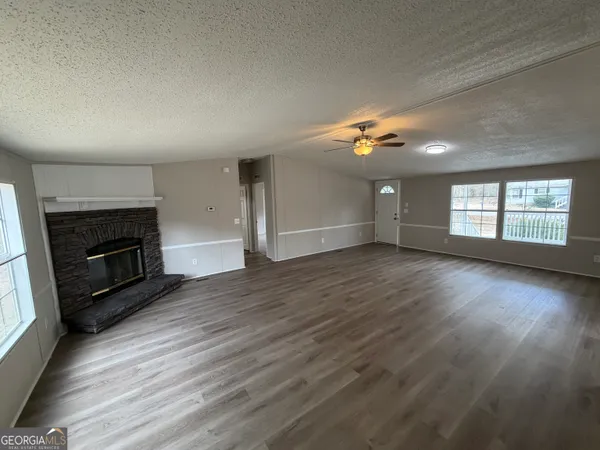 an empty room with wooden floor fireplace and windows