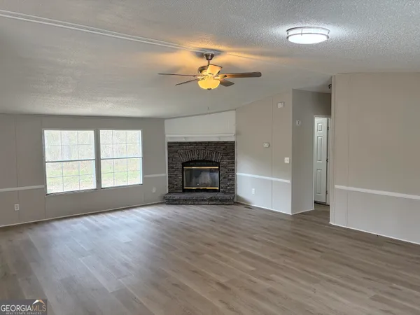 an empty room with wooden floor fireplace and windows
