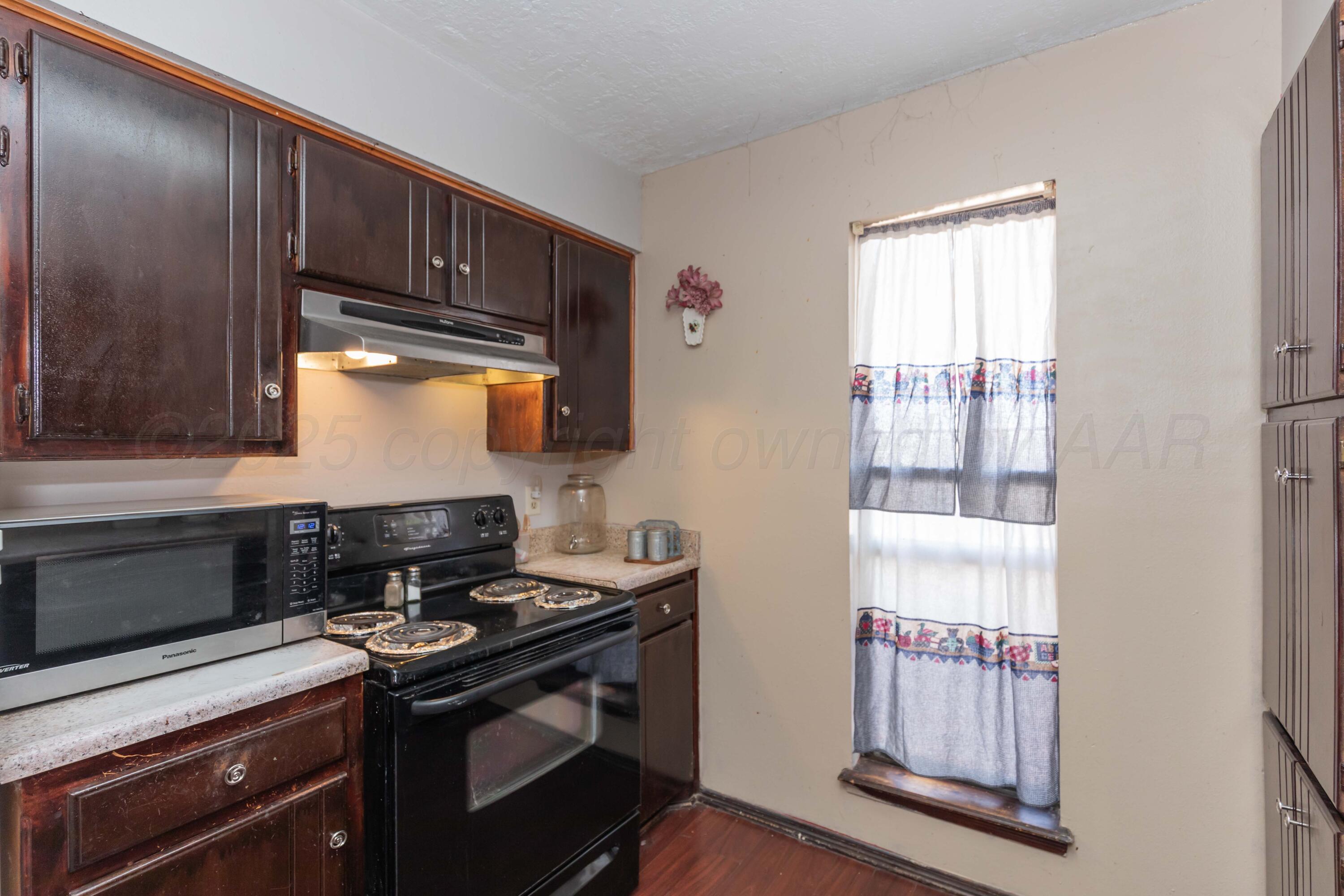 609 Groom Avenue Panhandle, TX 79068 - Photo 6 of 28 a kitchen with stainless steel appliances granite countertop a stove a sink and a microwave