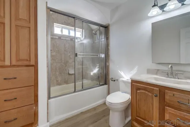 a view of a white house with a large tree with wooden fence