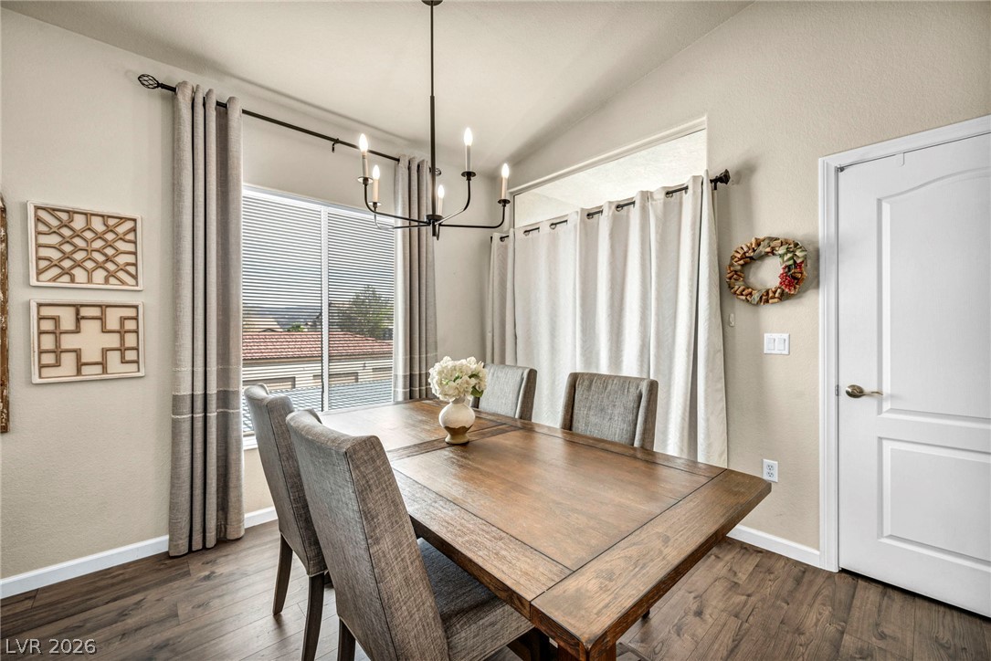 2305 West Horizon Ridge Parkway, Unit 3621 Henderson, NV 89052 - Photo 4 of 23 A refined dining space illuminated by a contemporary chandelier, showcasing rich hardwood flooring and a functional door.