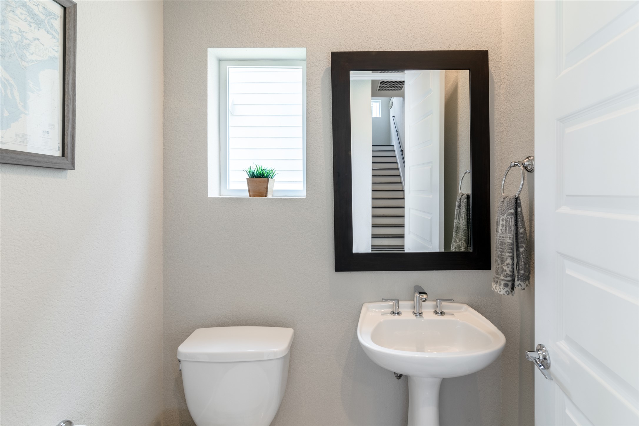 6025 Seville Drive Austin, TX 78724 - Photo 27 of 40 Main level half bath featuring a pedestal sink with chrome fixtures and a dark-framed mirror