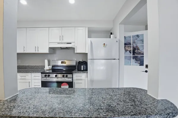 a kitchen with stainless steel appliances granite countertop a refrigerator sink and stove