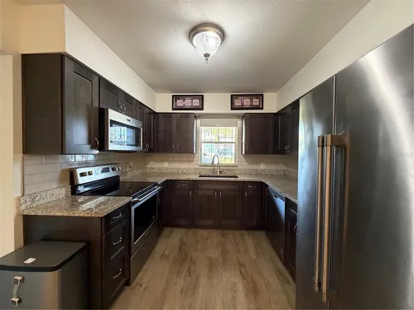 a kitchen with stainless steel appliances granite countertop a stove a sink and a refrigerator