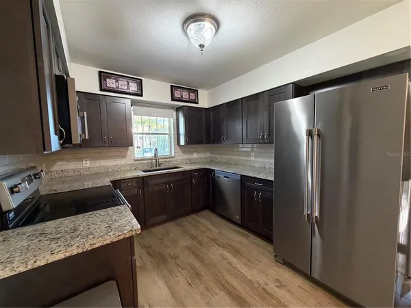 a kitchen with granite countertop stainless steel appliances a refrigerator and a sink