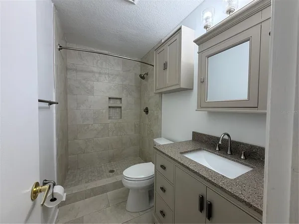 a bathroom with a granite countertop sink toilet and shower