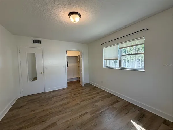 a view of an empty room with wooden floor and a window