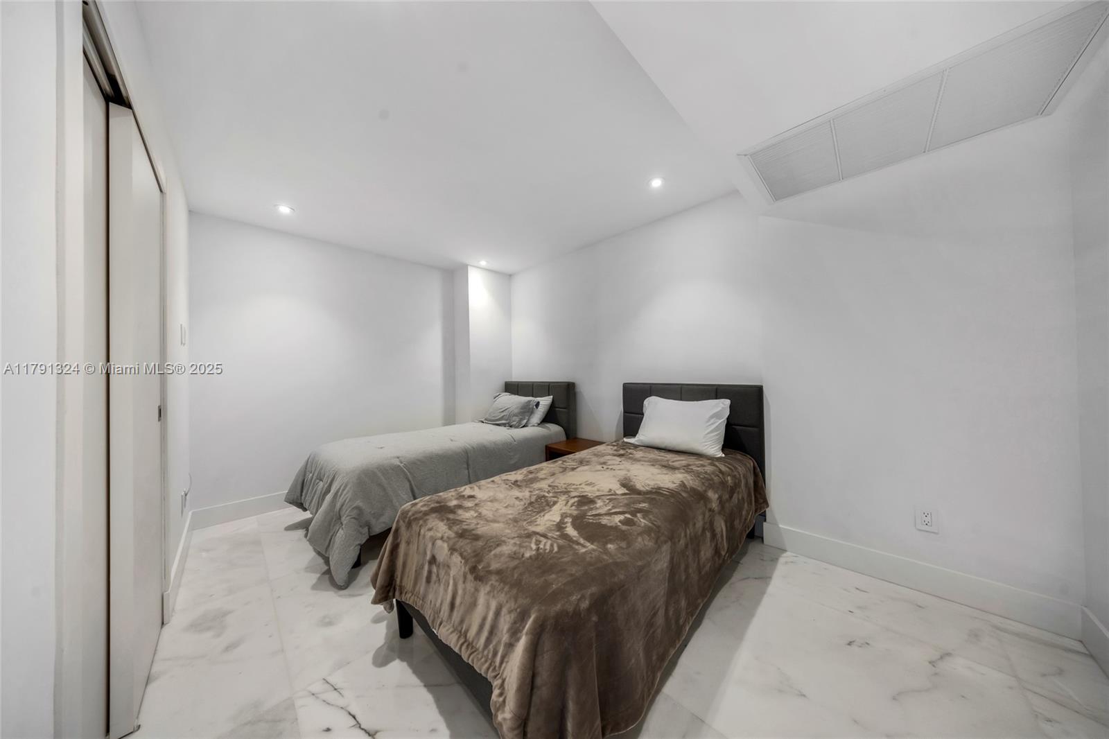 9801 Collins Avenue, Unit 17R Bal Harbour, FL 33154 - Photo 17 of 46 a bedroom with two beds and a lamp