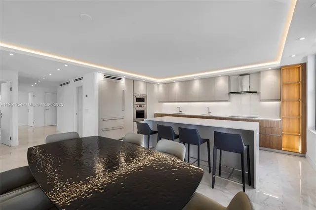 a living room with stainless steel appliances kitchen island granite countertop a sink and a refrigerator