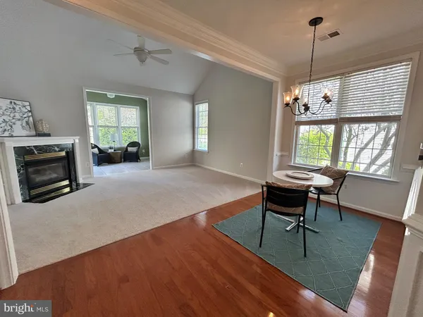 a dining room with wooden floor a chandelier a wooden table and chairs