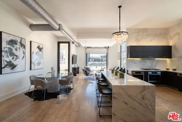 a large living room with stainless steel appliances granite countertop couches a fireplace with wooden floor