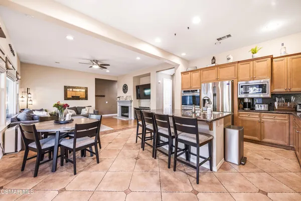a dining hall with stainless steel appliances kitchen island granite countertop a dining table chairs and view kitchen