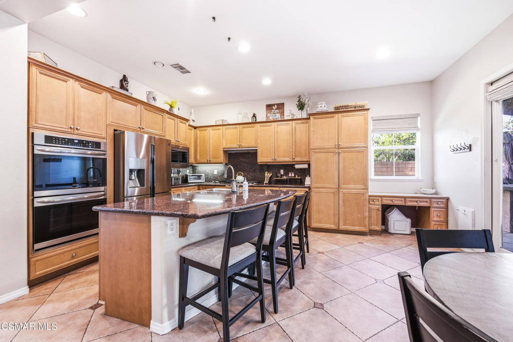 4741 Westwood Street Simi Valley, CA 93063 - Photo 10 of 50 a kitchen with stainless steel appliances kitchen island granite countertop a table chairs and a refrigerator
