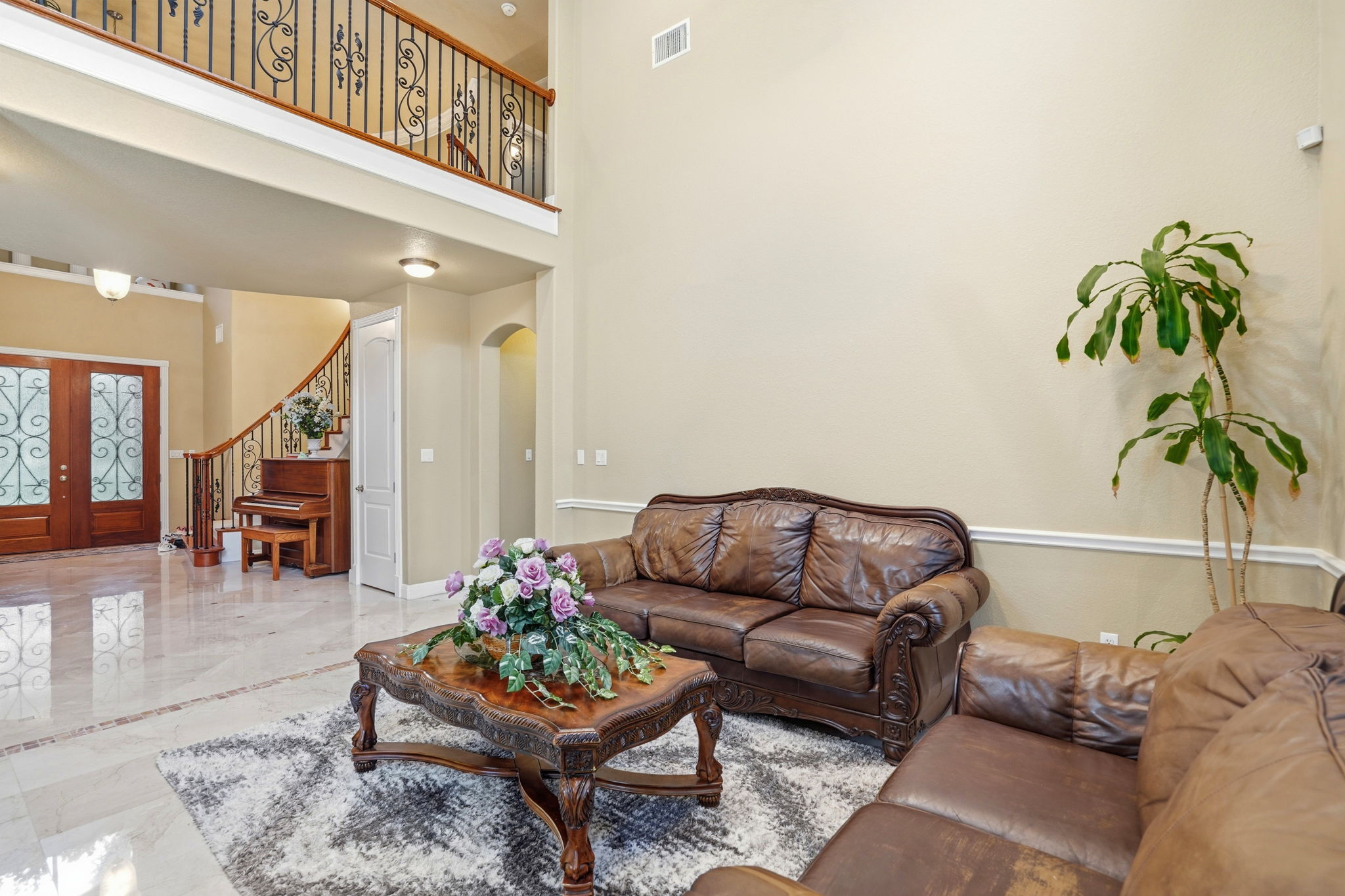 222 Vailco Lane Austin, TX 78738 - Photo 6 of 39 Two-story foyer featuring a double wood entry door with ornate glass inserts, a curved staircase with wrought iron balusters, and polished tile flooring with a decorative inlay