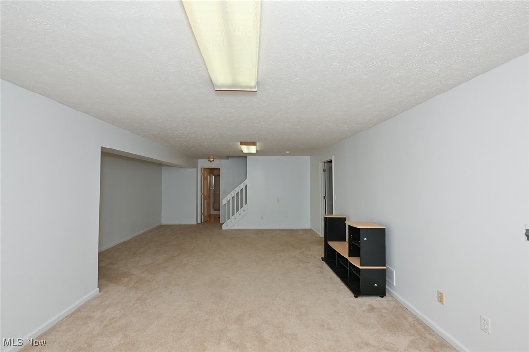 4212 Castle Ridge Akron, OH 44321 - Photo 38 of 44 Finished below grade area with stairway, light carpet, a textured ceiling, and baseboards