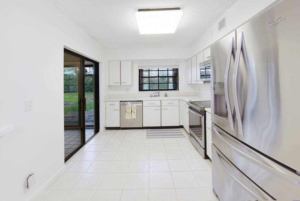 17340 Boca Club Boulevard, Unit 704 Boca Raton, FL 33487 - Photo 9 of 27 a kitchen with stainless steel appliances a refrigerator sink and cabinets