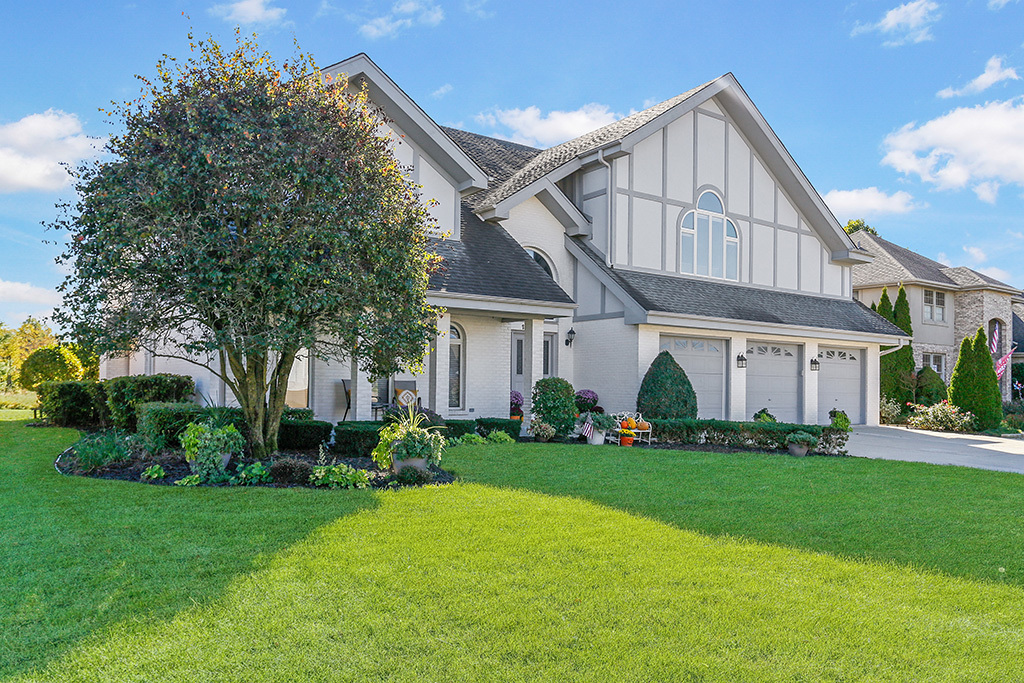 a front view of a house with a garden and trees