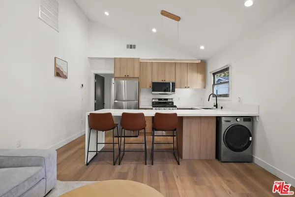 a kitchen with stainless steel appliances a stove a sink a microwave a refrigerator and cabinets