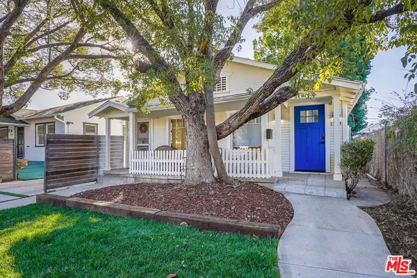 a view of a house with a yard and a large tree