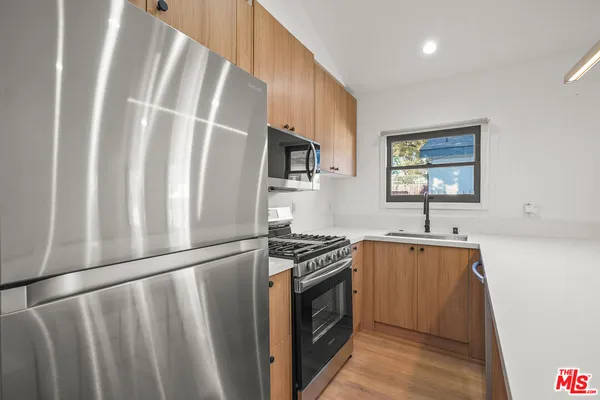 a kitchen with stainless steel appliances granite countertop a stove a sink dishwasher a refrigerator and a stove with wooden floor