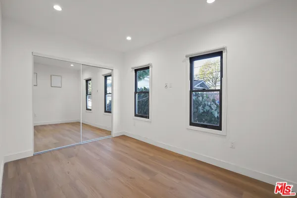 a view of empty room with wooden floor and windows