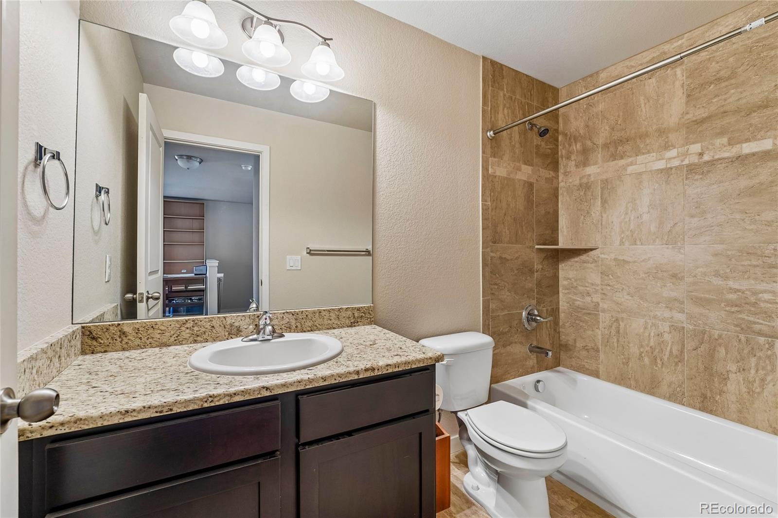 3611 South Perth Circle, Unit 102 Aurora, CO 80013 - Photo 23 of 40 a bathroom with a granite countertop sink toilet mirror and shower